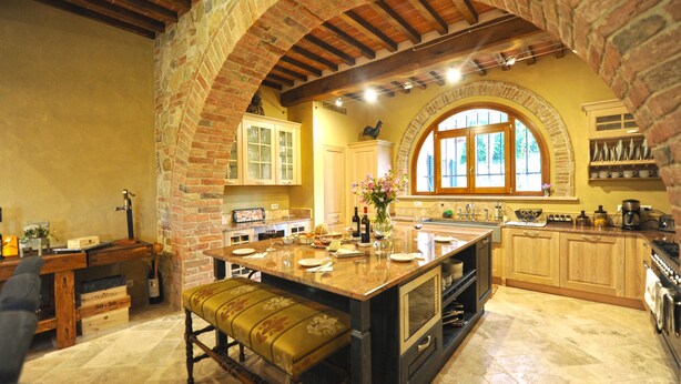 Una cocina con una isla grande, armarios de madera y un arco de piedra.
