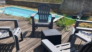 Een houten terras met buitenmeubilair en een zwembad.