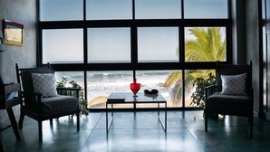 A room with a large window overlooking the ocean, two chairs, a table with a red heart-shaped object, and a framed picture on the wall. - "Villa Rocas" Beachfront Luxury Villa (El Pescadero)
