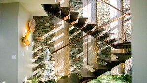 A modern staircase with a stone wall backdrop, a decorative wall piece, and a water feature at the bottom. - "Villa Rocas" Beachfront Luxury Villa (El Pescadero)
