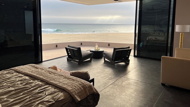 A bedroom with a large bed, a ceiling fan, and a view of the beach. - "Villa Rocas" Beachfront Luxury Villa (El Pescadero)