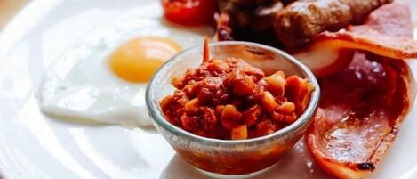 En tallrik med frukostmat, inklusive ägg, bacon, svamp och tomater.