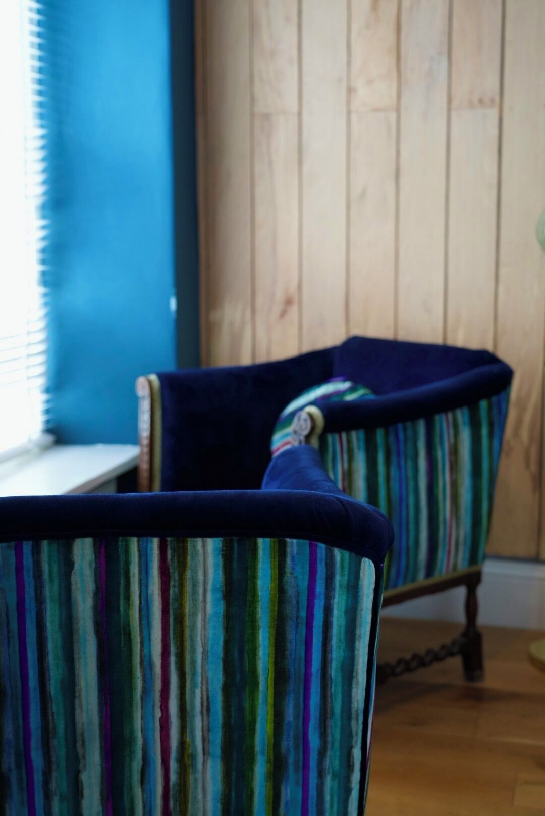 A room with two striped armchairs and a wooden floor.