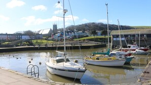 Uma marina com vários barcos atracados, uma ponte e uma igreja ao fundo.