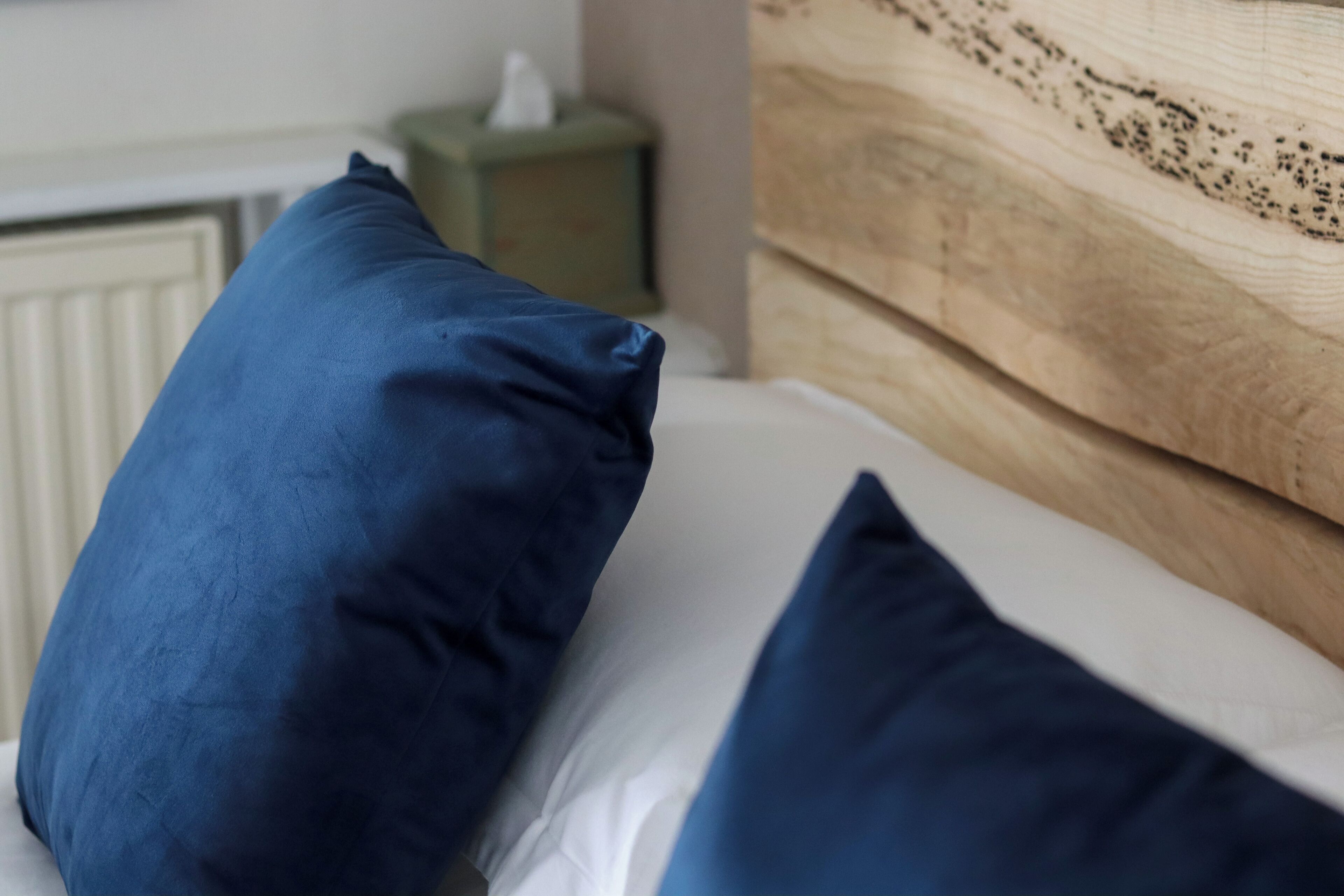 A bed with blue pillows and a wooden headboard.