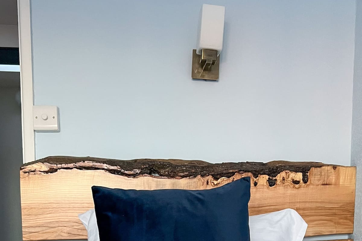 Un lit avec un oreiller bleu foncé, des oreillers blancs et une couvre-lit à motifs.
