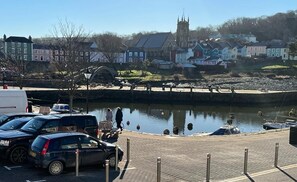 Una zona ribereña con coches estacionados, un muelle y una iglesia al fondo.