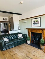 Una sala de estar con un sofá de cuero verde, una chimenea y un cuadro en la pared.