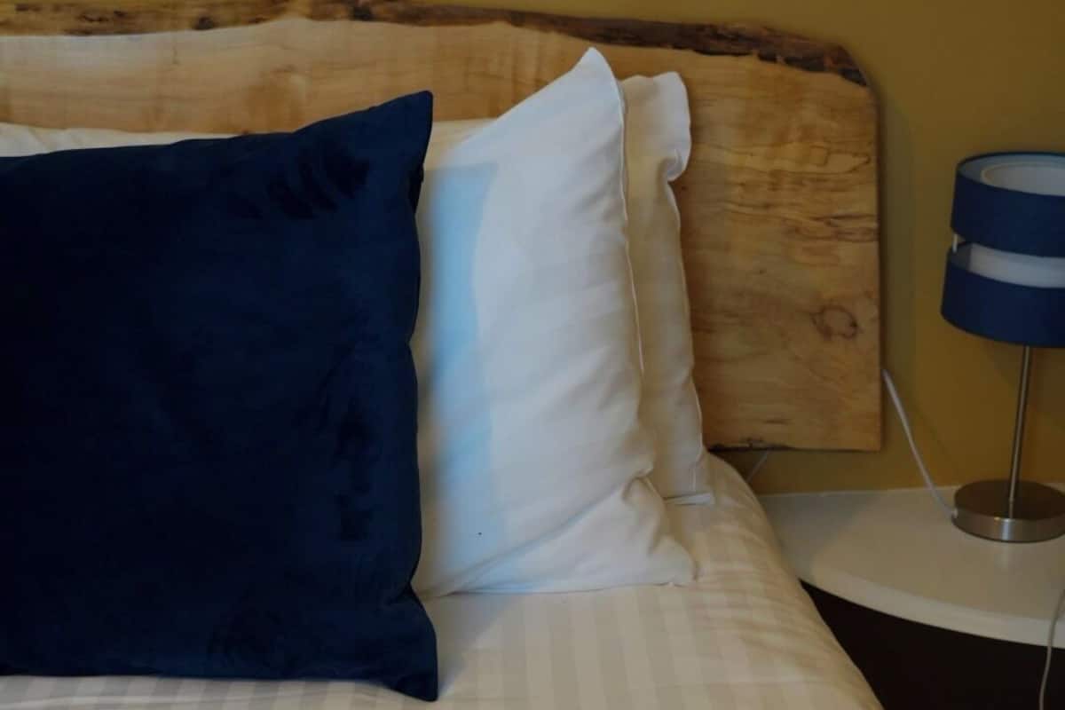 Un lit avec une literie à rayures, une tête de lit en bois et une lampe de chevet.
