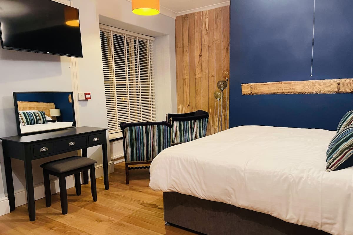 Une chambre à coucher avec un lit, un bureau, une chaise et un téléviseur fixé au mur.