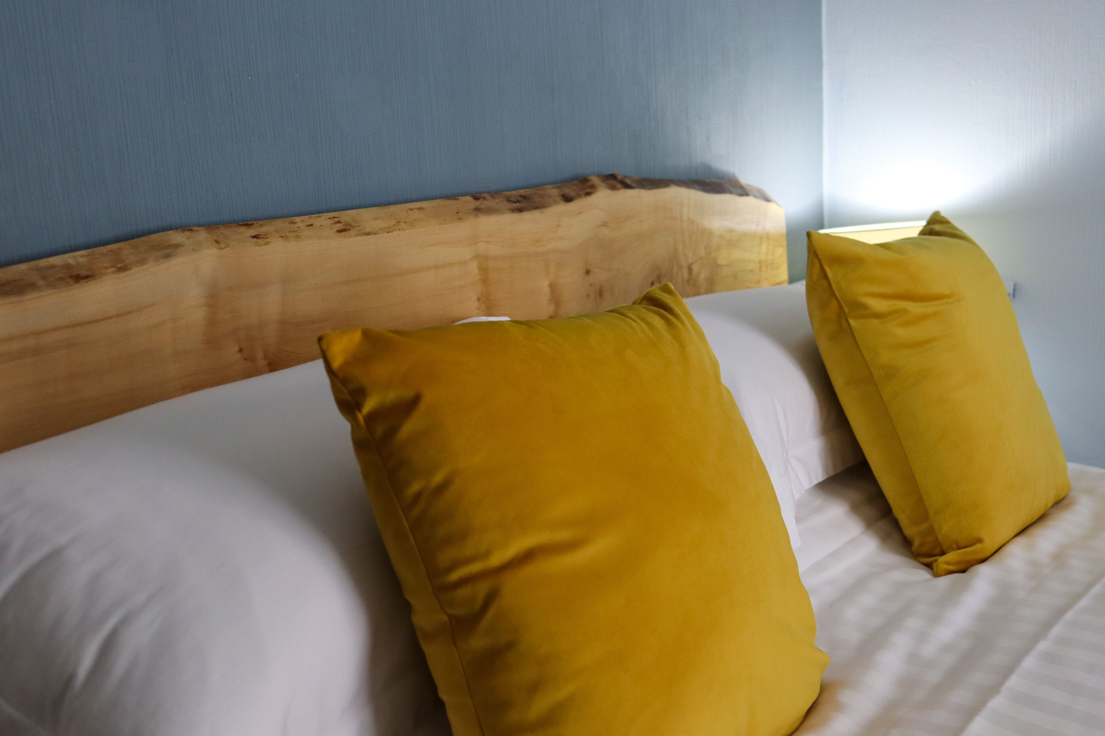 A bed with a wooden headboard and two yellow pillows.