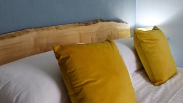 A bed with a wooden headboard and two yellow pillows.