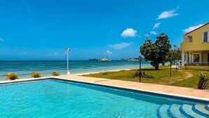 Une piscine d’un bleu éclatant, avec vue sur l’océan, et un bâtiment orné de colonnes.