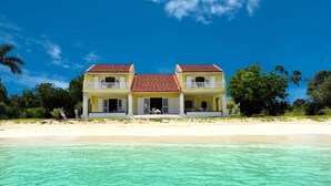 Une propriété de deux étages située en bord de mer, dotée d’un balcon, d’une terrasse couverte et offrant une vue sur l’océan.