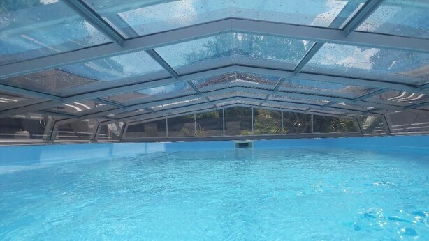 An indoor swimming pool with a glass ceiling and clear blue water. - Chalet 4 people with shared pool (Hourtin)