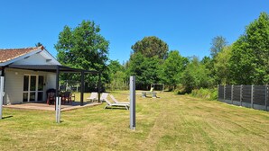 A house with a patio, outdoor seating, and a fenced yard. - Chalet 4 people with shared pool (Hourtin)