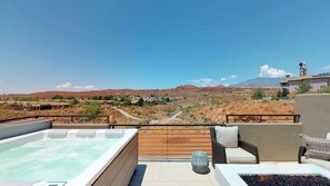 A hot tub on a rooftop terrace with a view of a desert landscape.