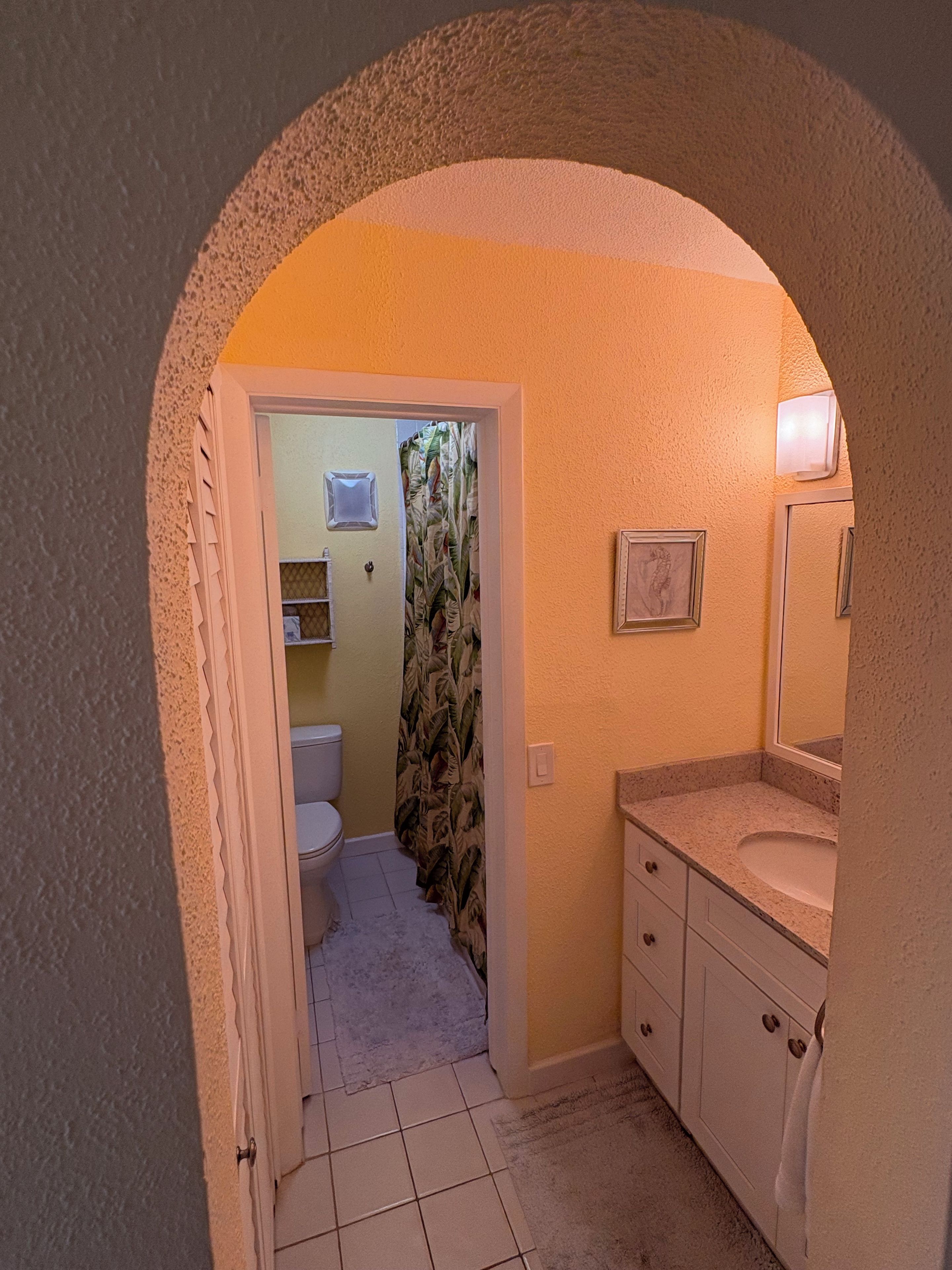 Un baño con inodoro, lavamanos y cortina de ducha.