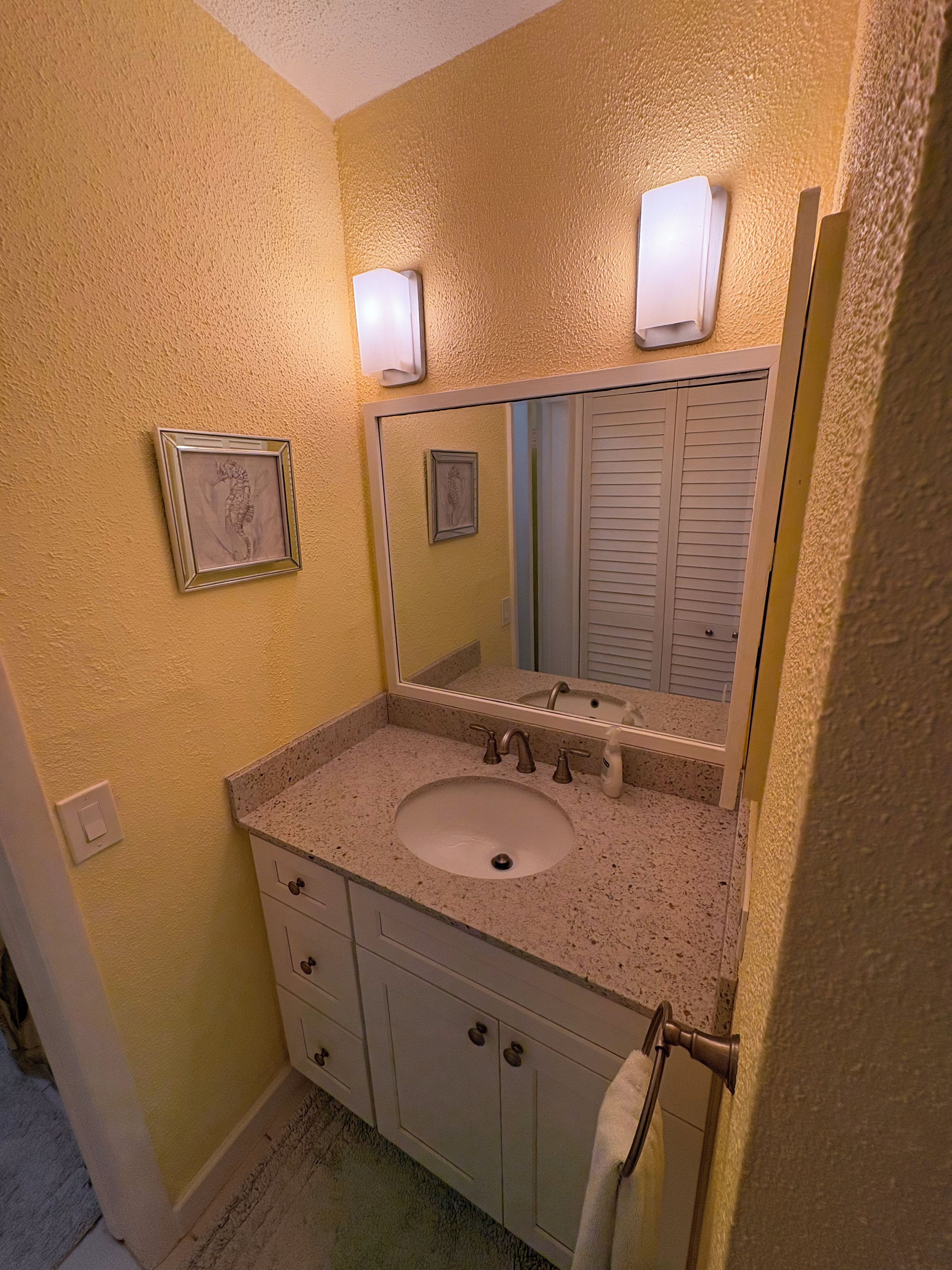 Une salle de bain avec un lavabo, un miroir et deux tableaux encadrés accrochés au mur.