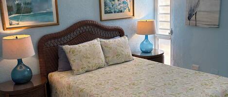 A bedroom with a bed, two nightstands, a ceiling fan, and wall art.