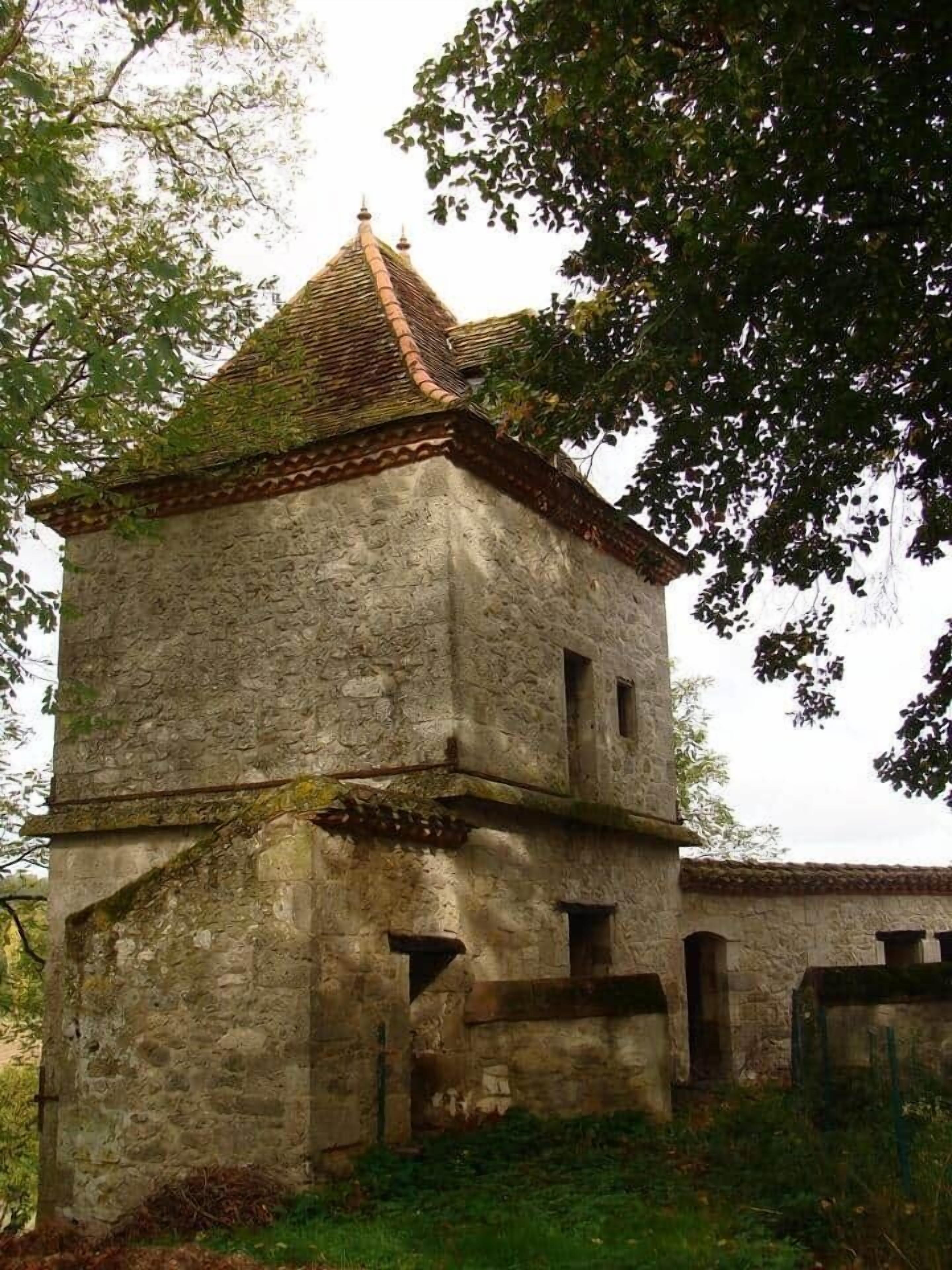 A stone building with a tiled roof, a small entrance, and a window.