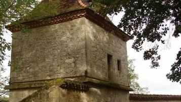 A stone building with a tiled roof, a small entrance, and a window.