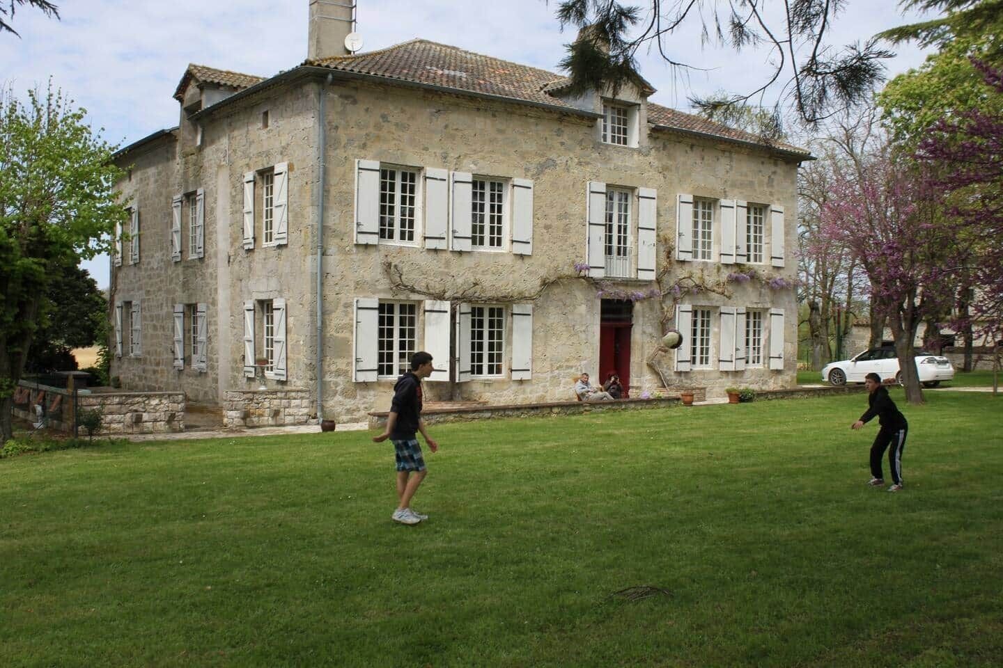 Un bâtiment en pierre doté de nombreuses fenêtres et d’une porte rouge.