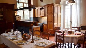A dining area with wooden cabinets, a kitchen in the background, and a table set for a meal.