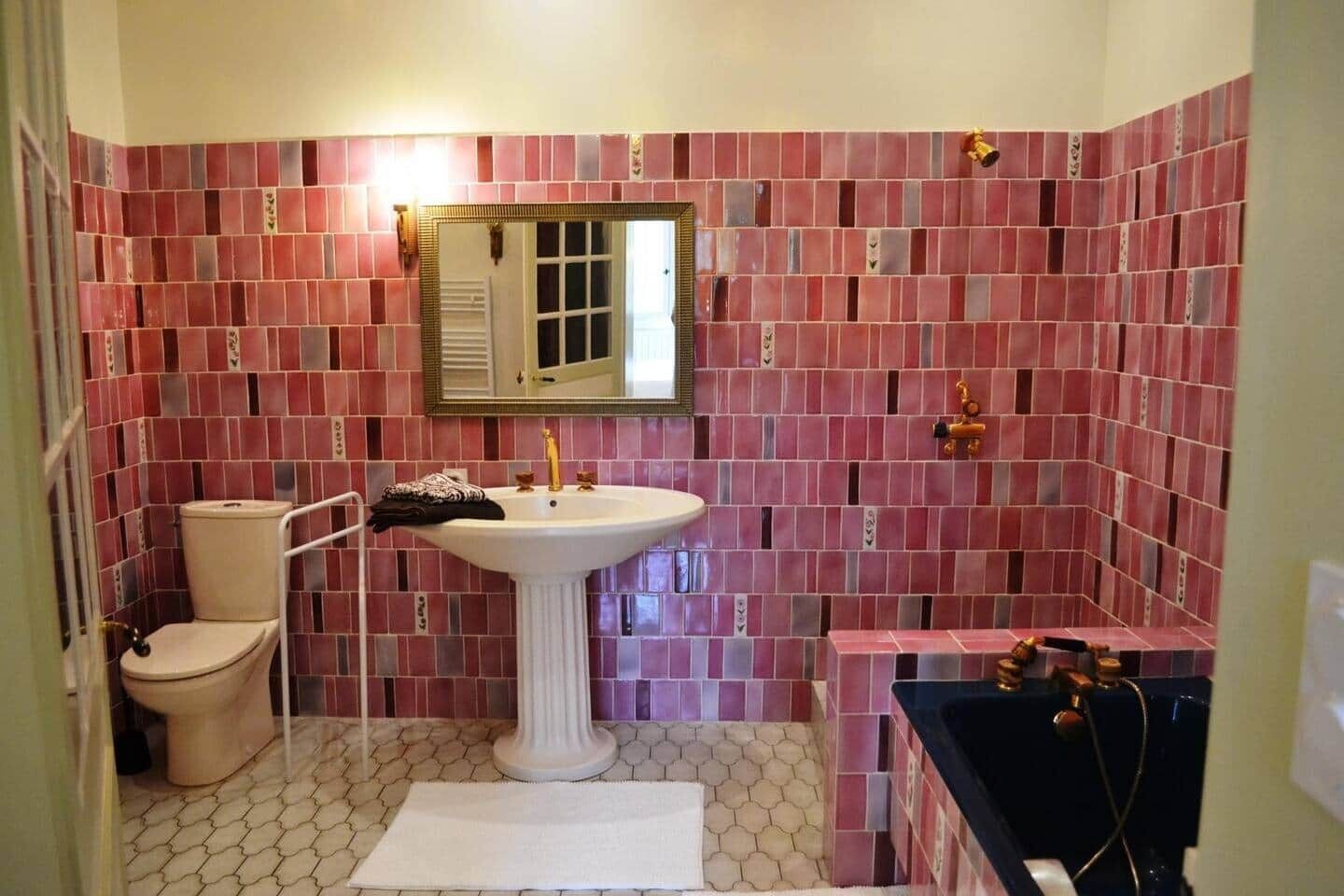 Een badkamer met een wastafel op voetstuk, toilet en bad.