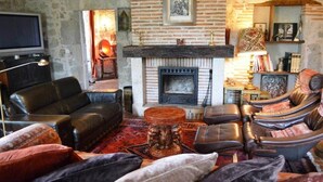 A cozy living room with a fireplace, leather sofas, and a television.