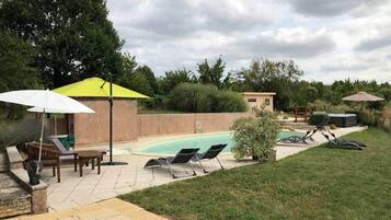 Un jardin avec une piscine, des chaises longues et un patio couvert.