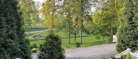 A view from a balcony overlooking a well-maintained garden with a gravel path, neatly trimmed hedges, and a variety of trees.