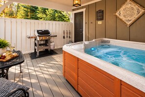 A hot tub on a wooden deck with a grill and a table with food and drinks. - Quiet, Family-Run Cottage Near Asheville (Asheville)