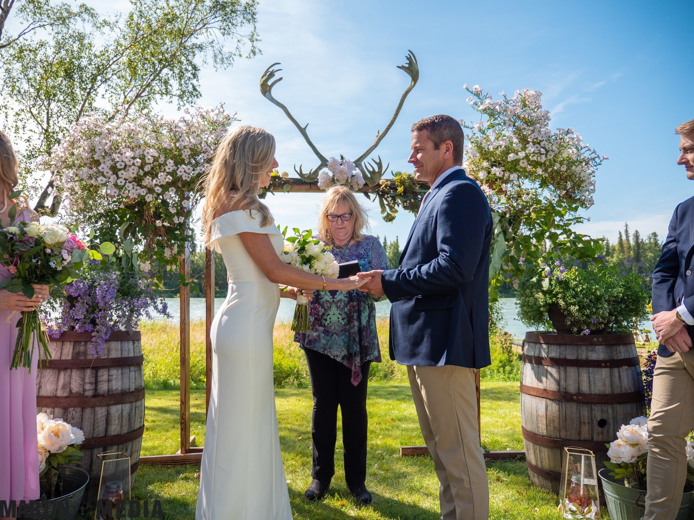 A wedding ceremony outdoors with a lake in the background.