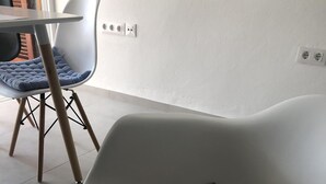 Un fauteuil moderne doté d’un dossier rembourré et de pieds en métal, placé dans une pièce dont le sol est carrelé et qui contient une table entourée de chaises.