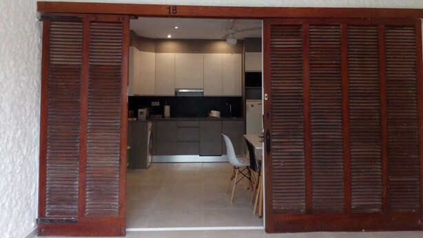 Une cuisine moderne dotée de portes coulissantes en bois, un coin repas avec une table et des chaises blanches, et le chiffre « 18 » bien visible sur le cadre de la porte.
