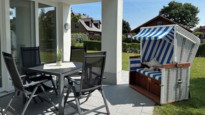 An outdoor patio with a table and chairs, a wicker chair with a striped canopy, and a view of the surrounding neighborhood.