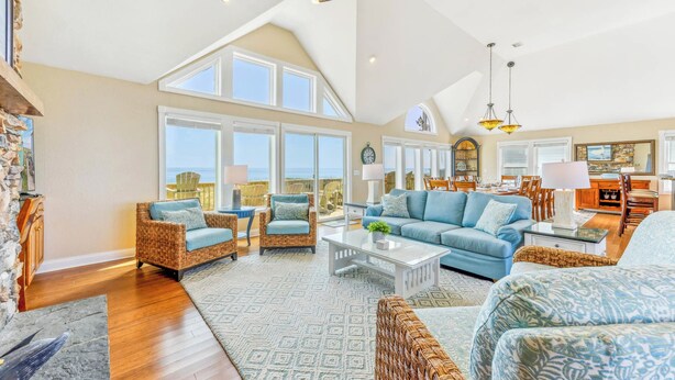 A spacious living room with high ceilings, large windows, and a view of the ocean. - Premier Oceanfront Dog Friendly Home w/ Pool, Hot Tub, EV Charger, and Game Room (Hatteras)