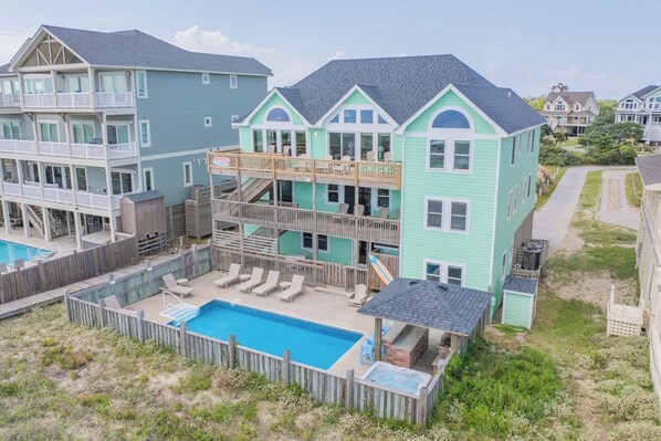 A two-story house with a pool, a deck, and a hot tub.