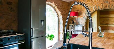 A kitchen with a stainless steel refrigerator, a gas stove, and a modern sink with a high-arc faucet.