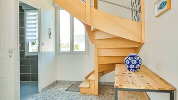 Un intérieur moderne avec un escalier en bois, un sol carrelé et un vase posé sur une table.