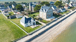 A coastal residential area with houses along a beachfront, featuring a prominent stone building with a large balcony.