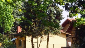 Una casa con fachada amarilla, techo rojo y patio cercado.