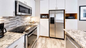 A modern kitchen with a built-in microwave, stainless steel refrigerator, and a coffee maker.