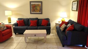A living room with a sofa set, a coffee table, a lamp, and a framed picture on the wall.