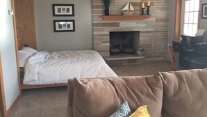 Un dormitorio con dos camas, una chimenea de piedra y un escritorio con computadora.