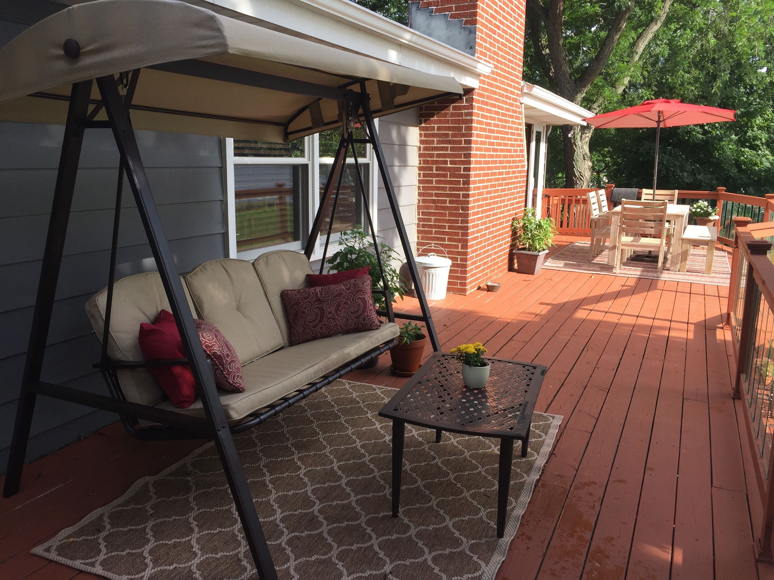 Un patio couvert avec une chaise suspendue, une table et du mobilier d’extérieur.