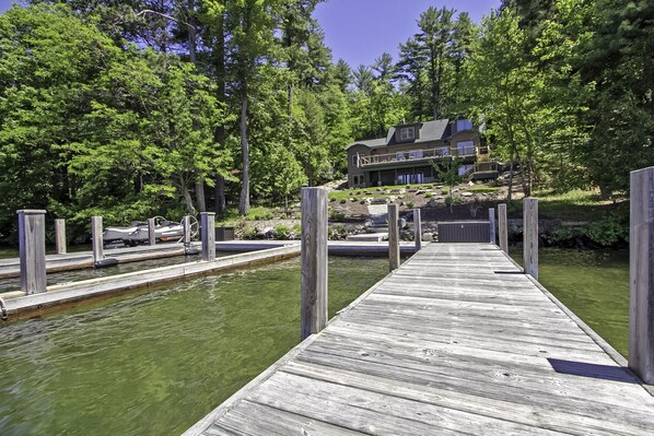 A wooden dock leading to a house surrounded by trees.