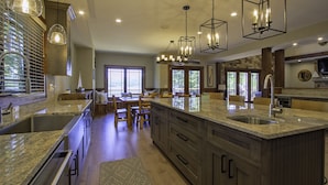 Una cocina amplia con encimeras de granito, gabinetes de madera e iluminación colgante.