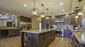 Una cocina moderna con encimeras de granito, electrodomésticos de acero inoxidable e iluminación colgante.